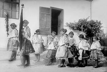 Hagyományos magyar népviseletbe öltözött gyermekek zászlóval Gyermekek hagyományos magyar népviseletben, zászlót tartva, valószínűleg ünnepi eseményen vagy felvonuláson.