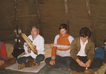 Hagyományos szertartás egy sátor belsejében Emberek ülnek egy sátor belsejében, egyikük egy dobhoz hasonló hangszert tart a kezében.