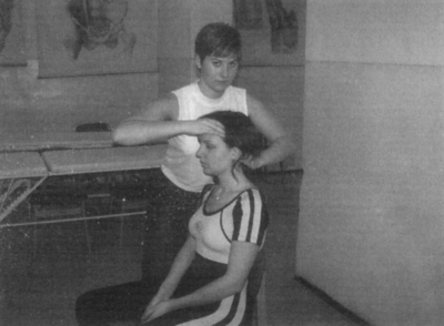 Hajigazítás anatómiai rajzokkal a háttérben Két ember, egyikük ül, a másik áll mögötte és a haját igazítja, háttérben anatómiai rajzok.