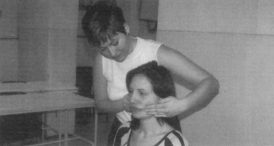 Hajigazítás beltéri környezetben Egy személy haját igazítja egy másik személy, háttérben asztal és falak láthatók.