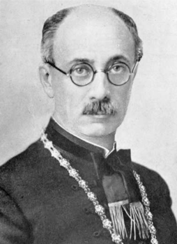 Hivatalos öltözet díszes lánccal Egy hivatalos öltözetet viselő személy díszes lánccal a nyakában.