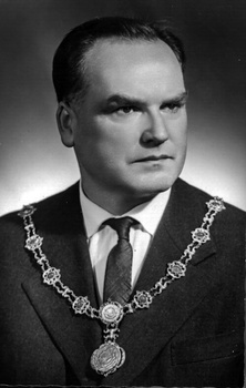 Hivatalos személy ünnepi öltözetben, nyakában díszes lánccal, jelvénnyel.