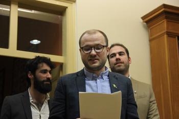 Hivatalos eseményen beszédet olvasó személyek Hivatalos eseményen résztvevő emberek, egyikük papírt tartva beszédet olvas fel.