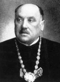 Hivatalos személy díszes lánccal Egy hivatalos személy díszes láncot visel a nyakában, hivatalos öltözetben.