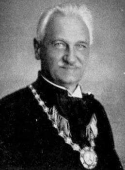 Hivatalos személy ünnepi öltözetben Hivatalos személy ünnepi öltözetben, nyakában díszes lánccal és medállal.