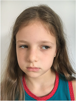 Hosszú hajú gyermek kék és piros szegélyű ruhában