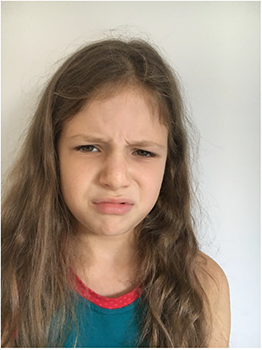 Hosszú, hullámos hajú személy kék ujjatlan felsőben, piros szegéllyel