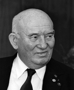 Idős férfi öltönyt visel, kitüntetésekkel a zakóján, fekete-fehér kép.