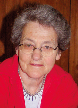 Idős nő piros ruhában nyaklánccal Idős nő piros ruhában, szürke hajjal, nyaklánccal, fa háttér előtt