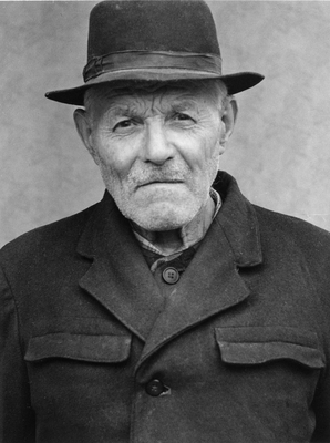 Egy férfi kalapot visel, kabátot és inget hord.