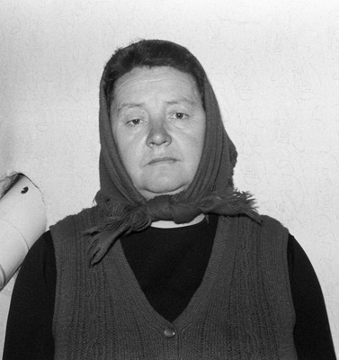 Egy kendőt viselő személy látható, aki egy kötött mellényt visel.