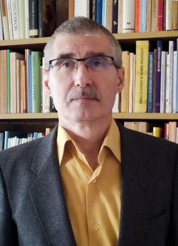 Könyvespolc tele könyvekkel és egy személy öltönyben Könyvespolc tele különböző könyvekkel, előtte egy öltönyös személy áll.