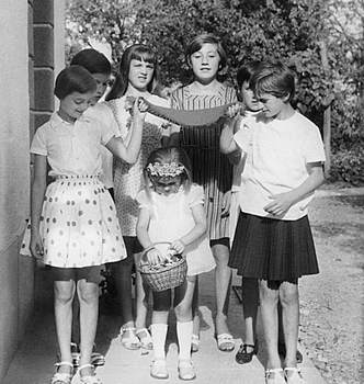 Lányok játék közben, kosárral és kendővel Hat lány látható, akik egy játékot játszanak, középen egy kislány kosarat tart, a többiek kendőt tartanak a feje fölött.