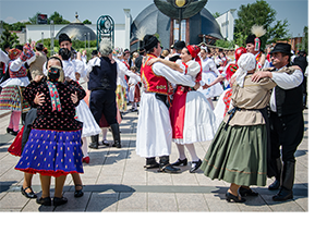 Magyar néptáncosok népviseletben Emberek magyar népviseletben táncolnak egy szabadtéri rendezvényen.