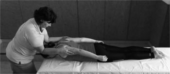 Terapeuta masszázst vagy fizikoterápiát végez egy fekvő személy hátán.