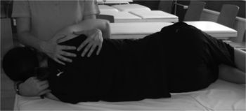 Egy személy fekszik az oldalán, miközben egy másik személy a hátát masszírozza vagy kezeli.