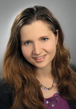 Nő hosszú barna hajjal, lila felsőben és nyaklánccal Egy nő hosszú barna hajjal, lila felsőben és nyaklánccal látható a képen.