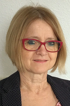 Nő szőke hajjal és piros szemüveggel Nő szőke hajjal, piros szemüveget visel, sötétkék pöttyös blézert hord.