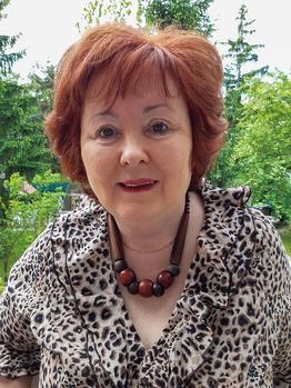 Nő állatmintás ruhában és fa gyöngyökből álló nyaklánccal Nő állatmintás ruhában, fa gyöngyökből álló nyaklánccal, zöld növényzet háttérrel