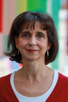 Nő piros felsőben színes háttér előtt Egy nő piros felsőt visel, háttérben színes csíkokkal.