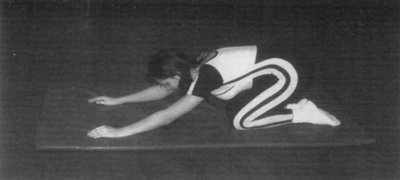 Nő tornaszőnyegen térdel és nyújtózkodik Egy nő tornaszőnyegen térdel, előre nyújtja karjait, mintha nyújtózkodna.