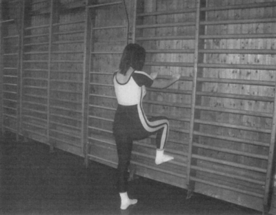 Nő tornatermi bordásfalon gyakorol Egy nő tornatermi bordásfalon gyakorol, sportos ruhában, edzés közben.