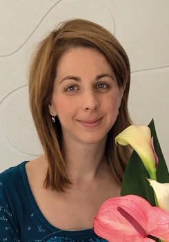 Egy nő virágcsokrot tart, benne rózsaszín flamingóvirág és fehér kála látható.