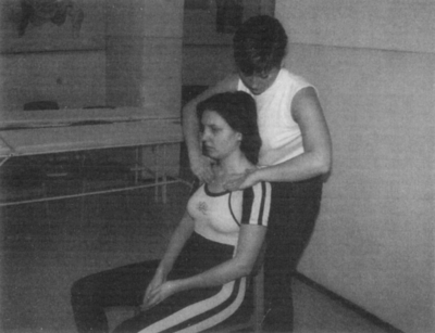 Nő masszírozza egy másik nő nyakát egy szobában Egy nő masszírozza egy másik nő nyakát egy szobában, relaxáció és fizikai terápia.