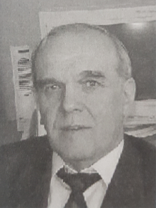 Öltönyös férfi könyvespolc háttérben Öltönyös férfi könyvespolc háttérben, nyakkendővel.