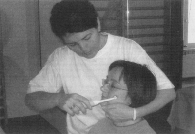 Orvosi kezelés fecskendővel Egy személy fecskendővel kezel egy másik személyt, a szájába fecskendezve valamit.