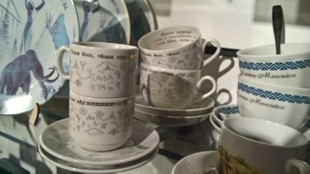 Porcelán csészék és tányérok vitrinben Különböző mintájú és feliratú porcelán csészék és tányérok egy üveges vitrinben.