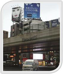 Roppongi utca Tokióban, ahol különböző reklámok és épületek láthatók, mint például a COCO塾 és hotel IBIS.