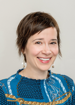 Rövid barna hajú személy kék mintás ruhában Rövid barna hajú személy kék mintás ruhában, gyöngyös fülbevalóval