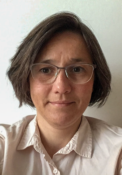 Egy személy rövid, barna hajjal és világos színű, galléros ingben.