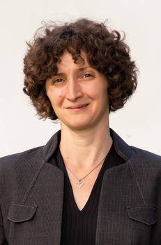 Személy sötét zakóban, szív medállal Személy sötét zakóban, fekete felsővel és szív alakú medállal a nyakában.