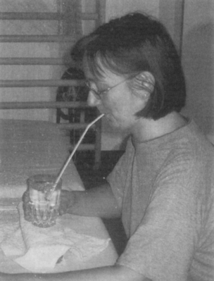 Személy vizet iszik szívószállal Egy személy pohár vizet iszik szívószállal, asztalnál ülve.