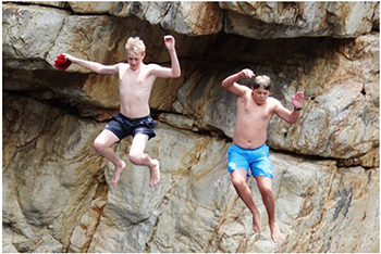 Két férfi sziklaugrás közben Két férfi ugrik le egy szikláról, egyikük fekete, másikuk kék nadrágban.