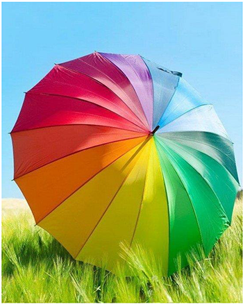 Színes esernyő a mezőn kék ég alatt Színes esernyő áll egy zöld mezőn, háttérben kék ég látható.