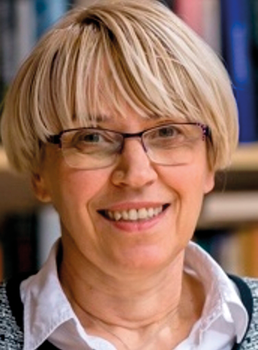 Szőke hajú személy könyvespolc előtt Szőke hajú személy fehér ingben, könyvespolcokkal a háttérben