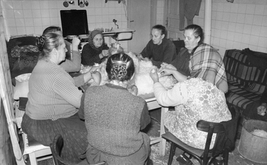 Csoport nő tollfosztást végez egy konyhában, hagyományos munka közben.