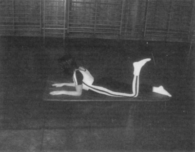 Tornagyakorlat fekvő helyzetben egy tornateremben Egy személy fekvő helyzetben tornagyakorlatot végez egy tornateremben.