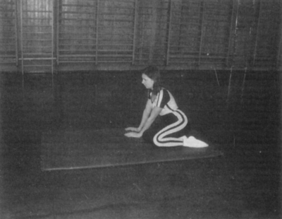 Személy sportöltözetben térdel egy tornateremben Egy személy sportöltözetben térdel egy matracon a tornateremben