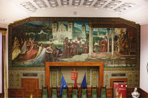 Történelmi falfestmény egy középkori koronázási jelenettel, magyar zászlókkal és címerrel.
