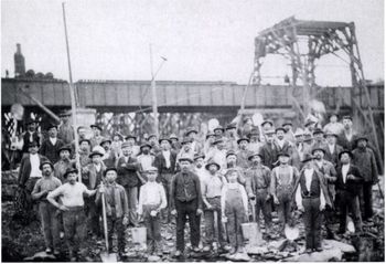 Történelmi munkáscsoport egy építkezésen Történelmi fotó munkásokról egy építkezésen, acélszerkezetes háttérrel