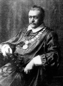 Történelmi személy díszes ruhában, könyvvel és lánccal Történelmi személy díszes ruhában, könyvet tartva, nyakában lánccal és medálokkal.