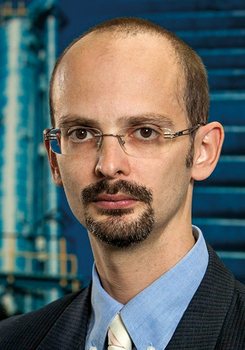 Üzletember öltönyben és nyakkendőben, háttérben egy modern épület látható