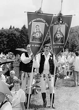 Vallási esemény magyar népviseletben, Szűz Mária és Jézus zászlókkal Szabadtéri vallási esemény, magyar népviseletbe öltözött emberek Szűz Mária és Jézus szíve zászlókkal