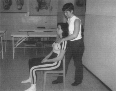 Vállmasszázs egy szobában orvosi poszterekkel Egy személy masszírozza egy másik személy vállát egy szobában, ahol orvosi poszterek láthatók a falon.