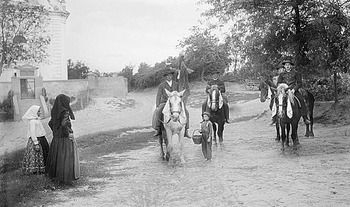 Vidéki lovasok haladnak el egy templom mellett Vidéki jelenet, ahol lovas emberek és gyalogosok haladnak el egy templom mellett.