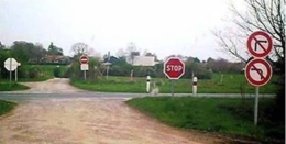 Vidéki útkereszteződés közlekedési táblákkal Vidéki útkereszteződés, ahol STOP tábla és kanyarodási tilalom táblák láthatók.